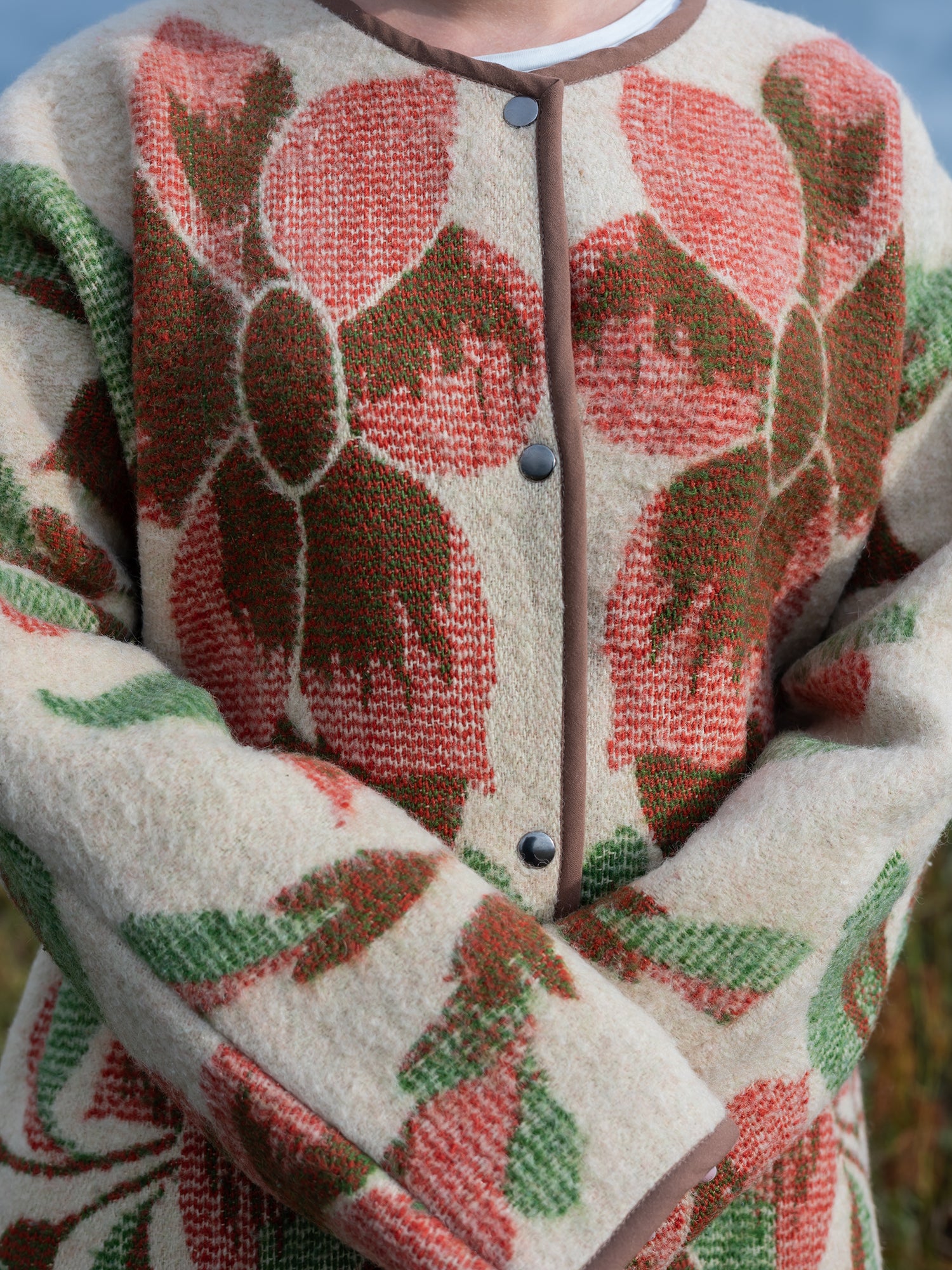 close-up wool texture rust green floral motif on cream base