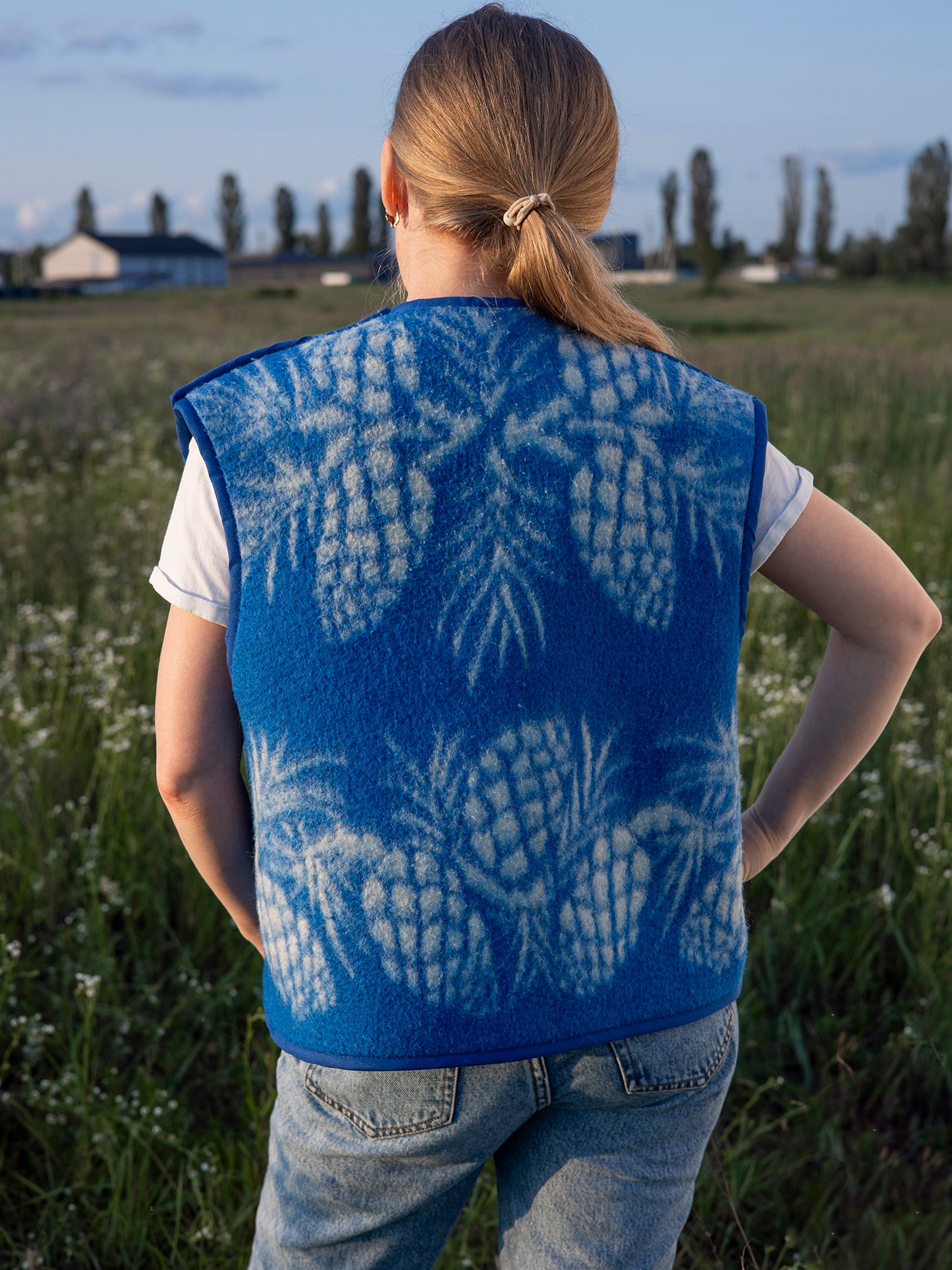 blue background and white pinecone motif close-up wool vest