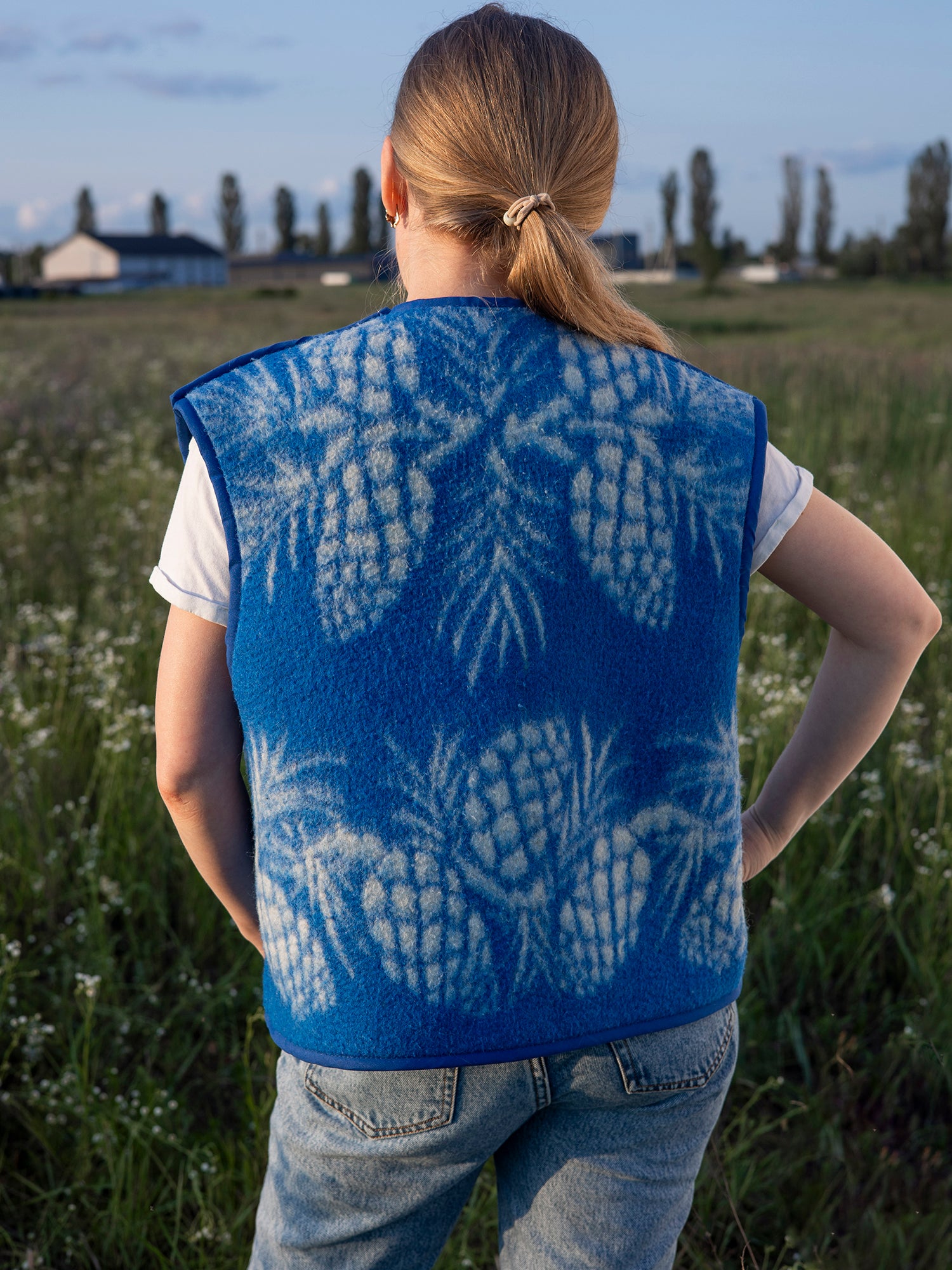 blue background and white pinecone motif close-up wool vest